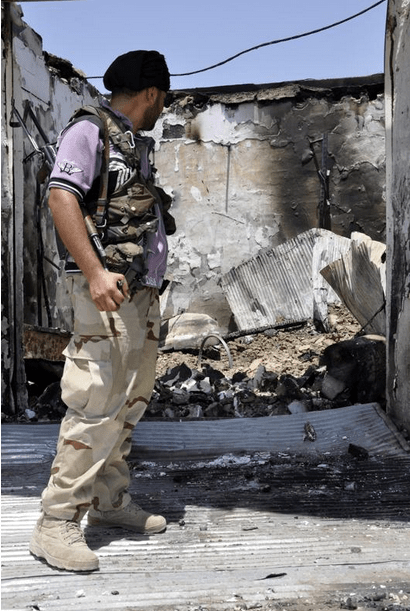 Member of the Iraqi security forces looks at burnt-out shops after clashes against militants of the Islamic State on the outskirts of Baquba